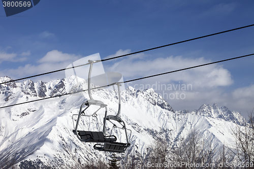 Image of Chair lift in snowy mountains at nice sunny day