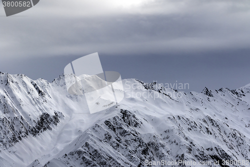 Image of High snowy mountains and sunlight storm sky before blizzard