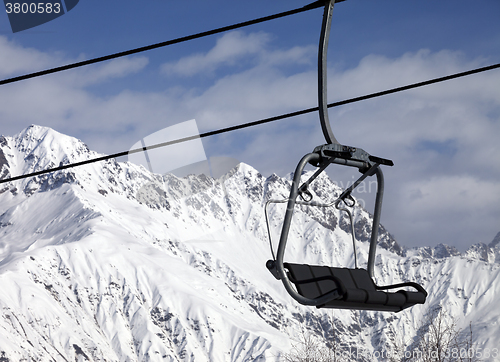 Image of Chair lift in snowy mountains at nice sunny day