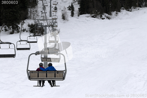 Image of Two skiers on chair-lift in gray day