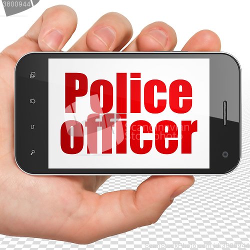 Image of Law concept: Hand Holding Smartphone with Police Officer on display