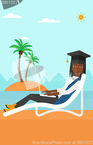 Image of Graduate lying on chaise lounge with laptop.