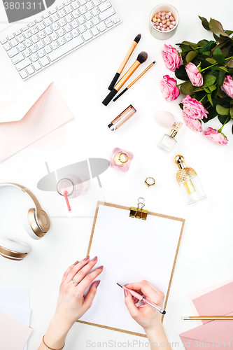 Image of The female hands writing against fashion woman objects