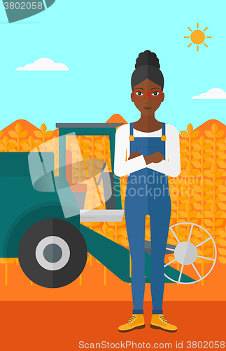 Image of Woman standing with combine on background.