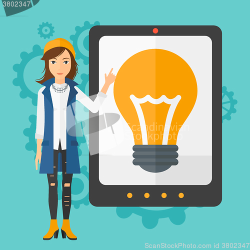 Image of Woman pointing at tablet computer with light bulb on screen.