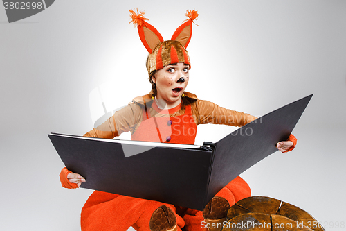 Image of Young woman in the image of red squirrel with big book