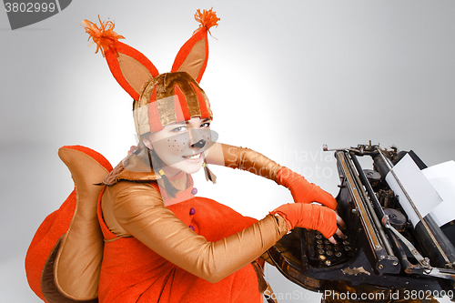 Image of Young woman in image of squirrel with a retro typewriter