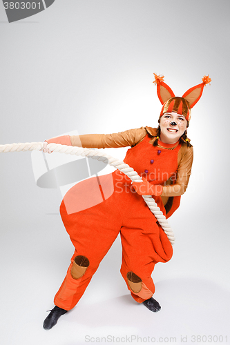 Image of Young woman in image of red squirrel pulling a rope