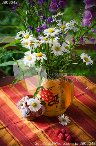 Image of A bouquet of daisies in a jug at the table