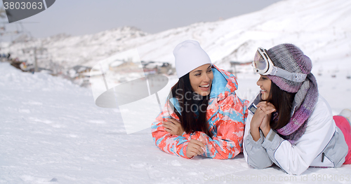 Image of Giggling twins laying down at ski slope