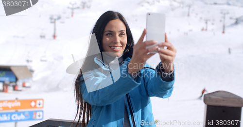 Image of Smiling young woman taking a winter selfie