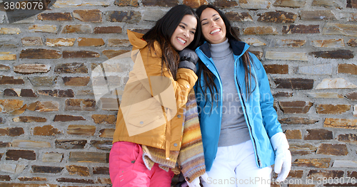 Image of Cute twins in winter coats leaning on wall