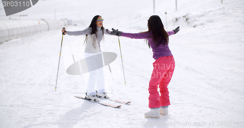 Image of Young woman teaching her friend to ski
