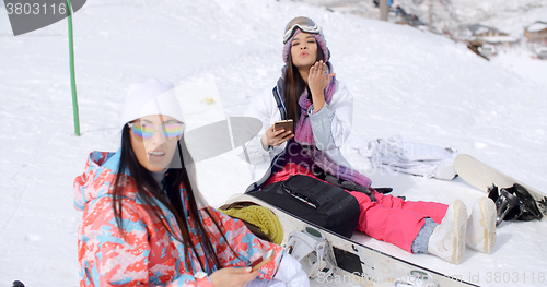 Image of Two attractive women snowboarders relaxing