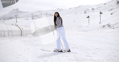 Image of Cute woman on skis at bottom of hill