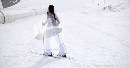 Image of Cute woman on skis at bottom of hill