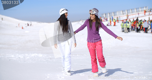 Image of Two attractive young woman walking in fresh snow