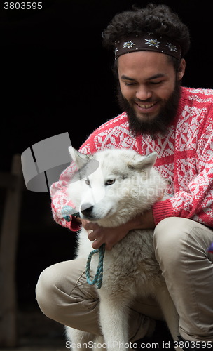 Image of young man playing with dog in front of wooden house