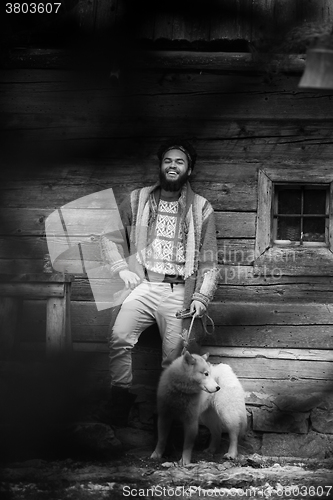 Image of hipster with dog in front of wooden house