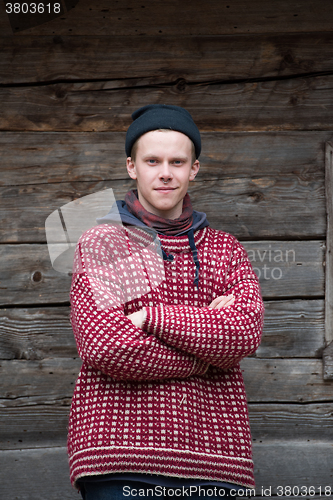 Image of young hipster in front of wooden house