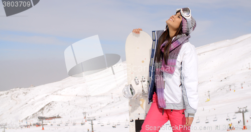 Image of Smiling gorgeous woman posing with her snowboard