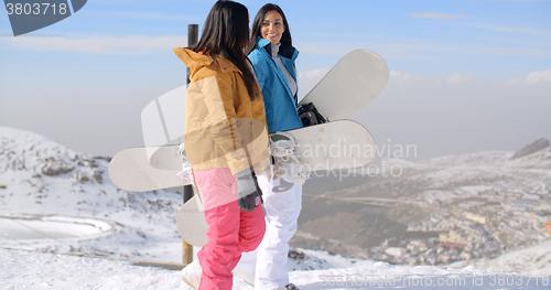 Image of Two women carrying their snowboards on a mountain