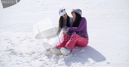 Image of Two young women sitting chatting in the snow