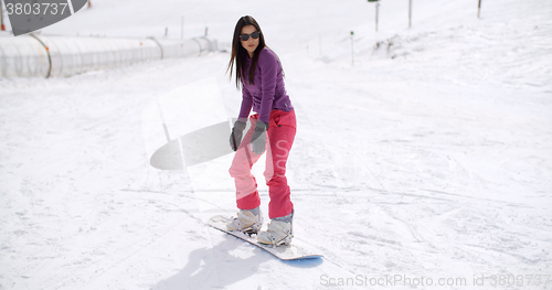 Image of Young woman standing balancing on a snowboard
