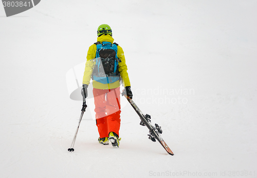 Image of Sad and weary skier goes away, dragging skis.