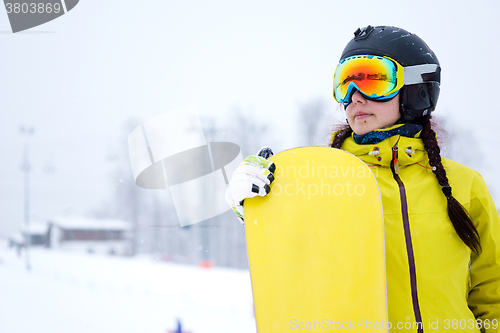 Image of Female snowboarder standing with snowboard