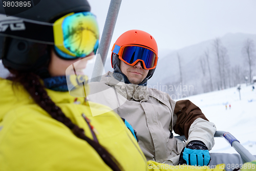 Image of Couple sitting on chairlift in mountain resorts.