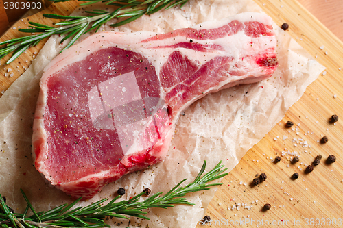 Image of Pieces of crude meat with rosemary and spices