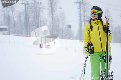 Image of Female skier standing with skies in one hand on background beautiful mountain landscape