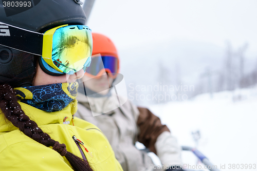 Image of Couple sitting on chairlift in mountain resorts.