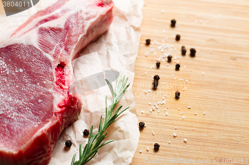 Image of Pieces of crude meat with rosemary and spices