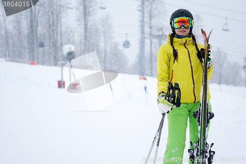 Image of Female skier standing with skies in one hand on background beautiful mountain landscape