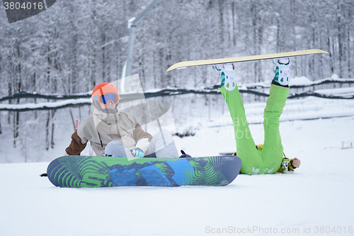 Image of Two snowboarders - men and women sitting in the mountains