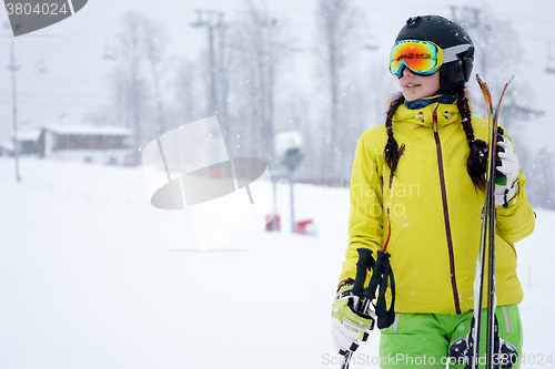 Image of Female skier standing with skies in one hand on background beautiful mountain landscape