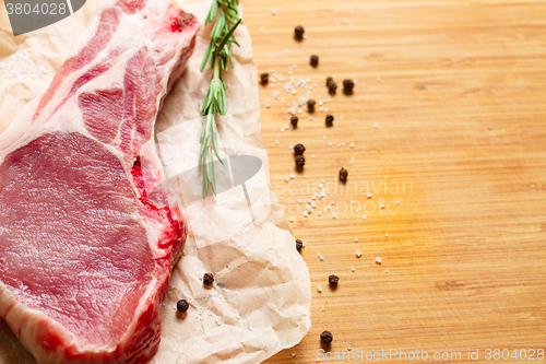 Image of Pieces of crude meat with rosemary and spices