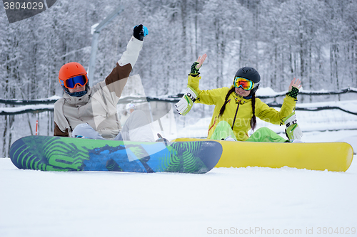 Image of Two snowboarders - men and women sitting in the mountains