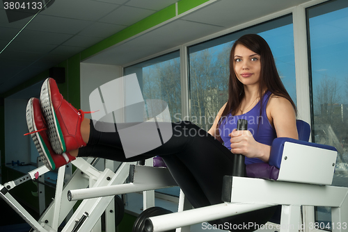 Image of Fit woman training press on simulator at gym