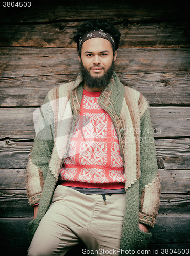 Image of portrait of young hipster in front of wooden house