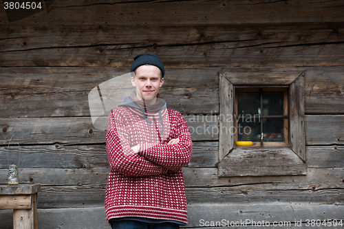 Image of young hipster in front of wooden house