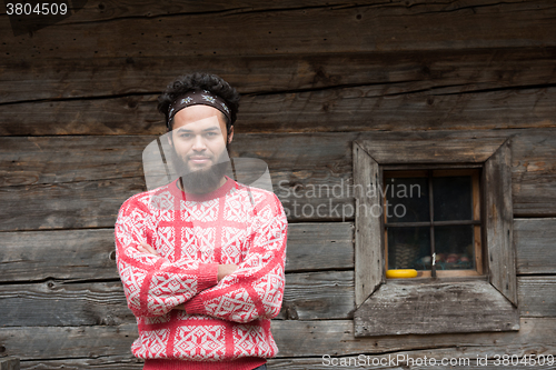 Image of portrait of young hipster in front of wooden house