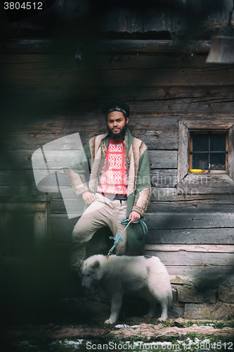 Image of hipster with dog in front of wooden house