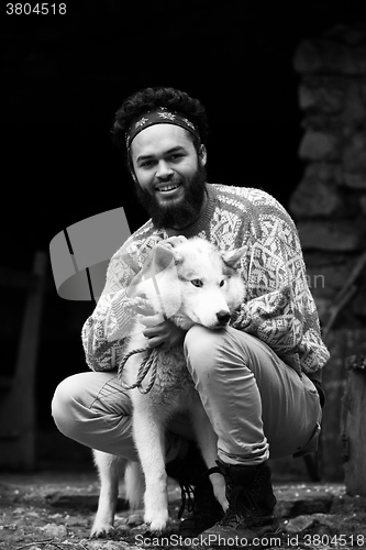 Image of hipster with dog in front of wooden house