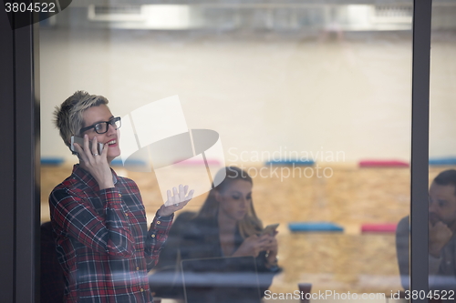 Image of business woman in meeting room  speaking by cell phone