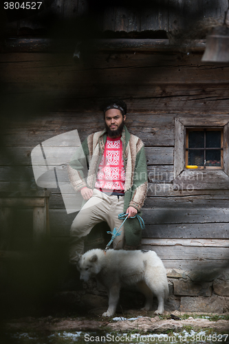 Image of hipster with dog in front of wooden house