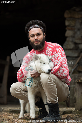 Image of hipster with dog in front of wooden house