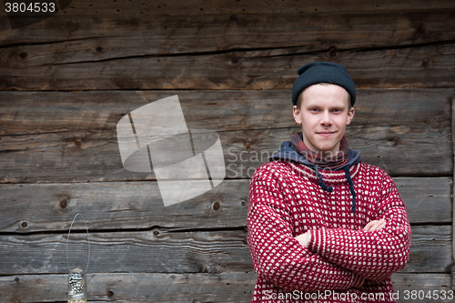 Image of young hipster in front of wooden house